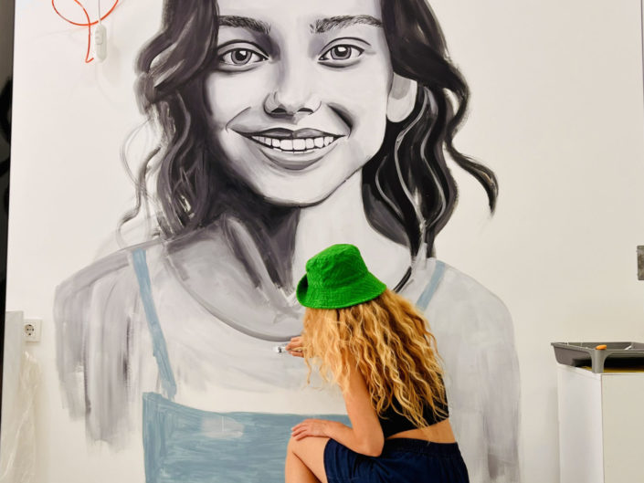 artist painting a portrait of a young Gil on an indoor mural in Istanbul