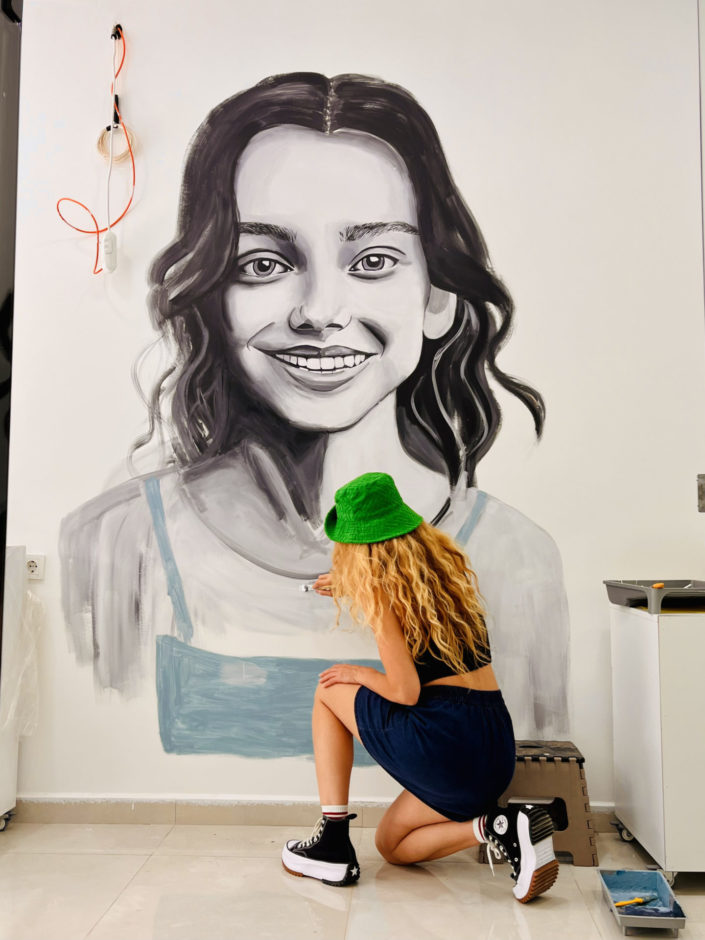 artist painting a portrait of a young Gil on an indoor mural in Istanbul